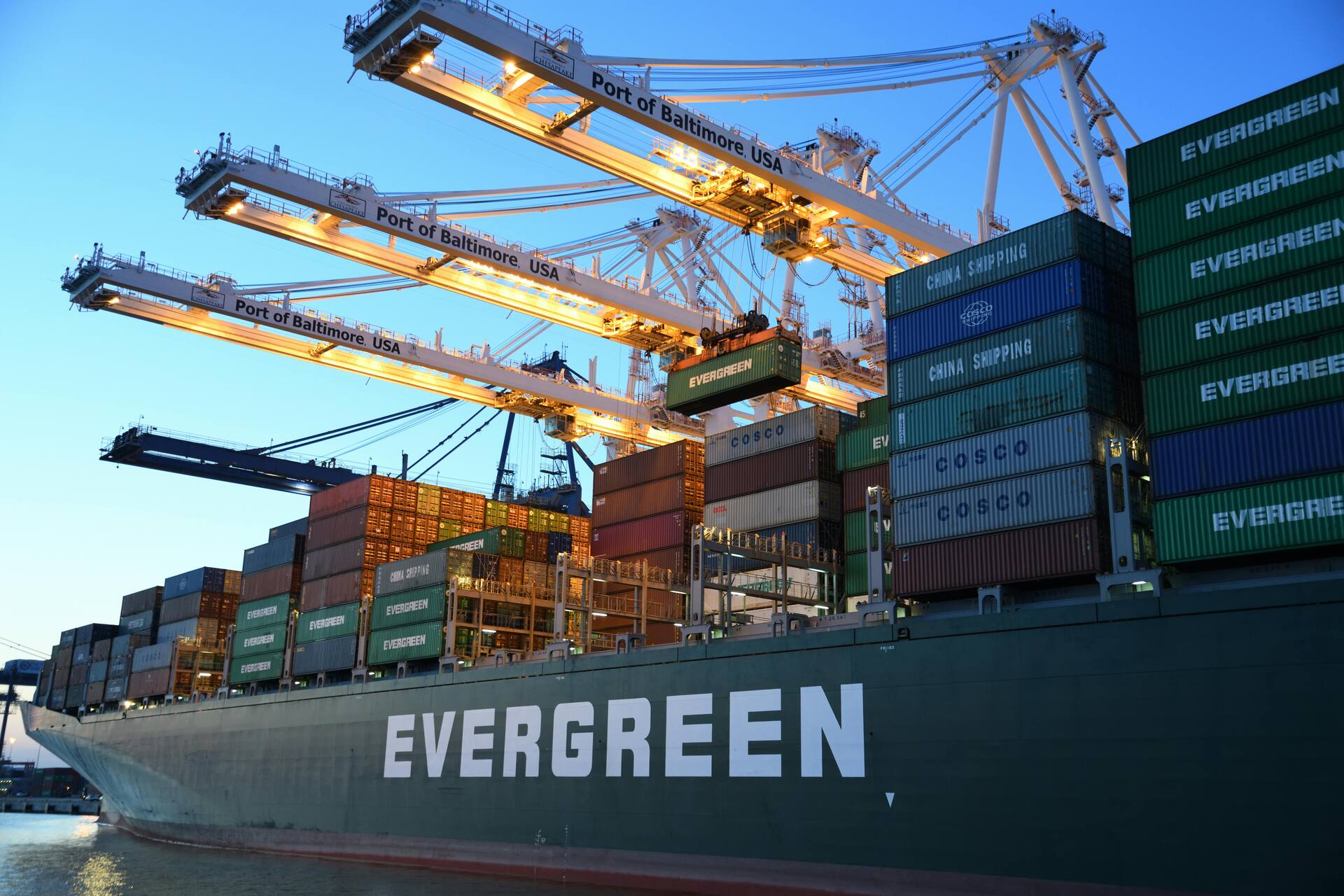 Container vessel loading under gantry cranes at dusk